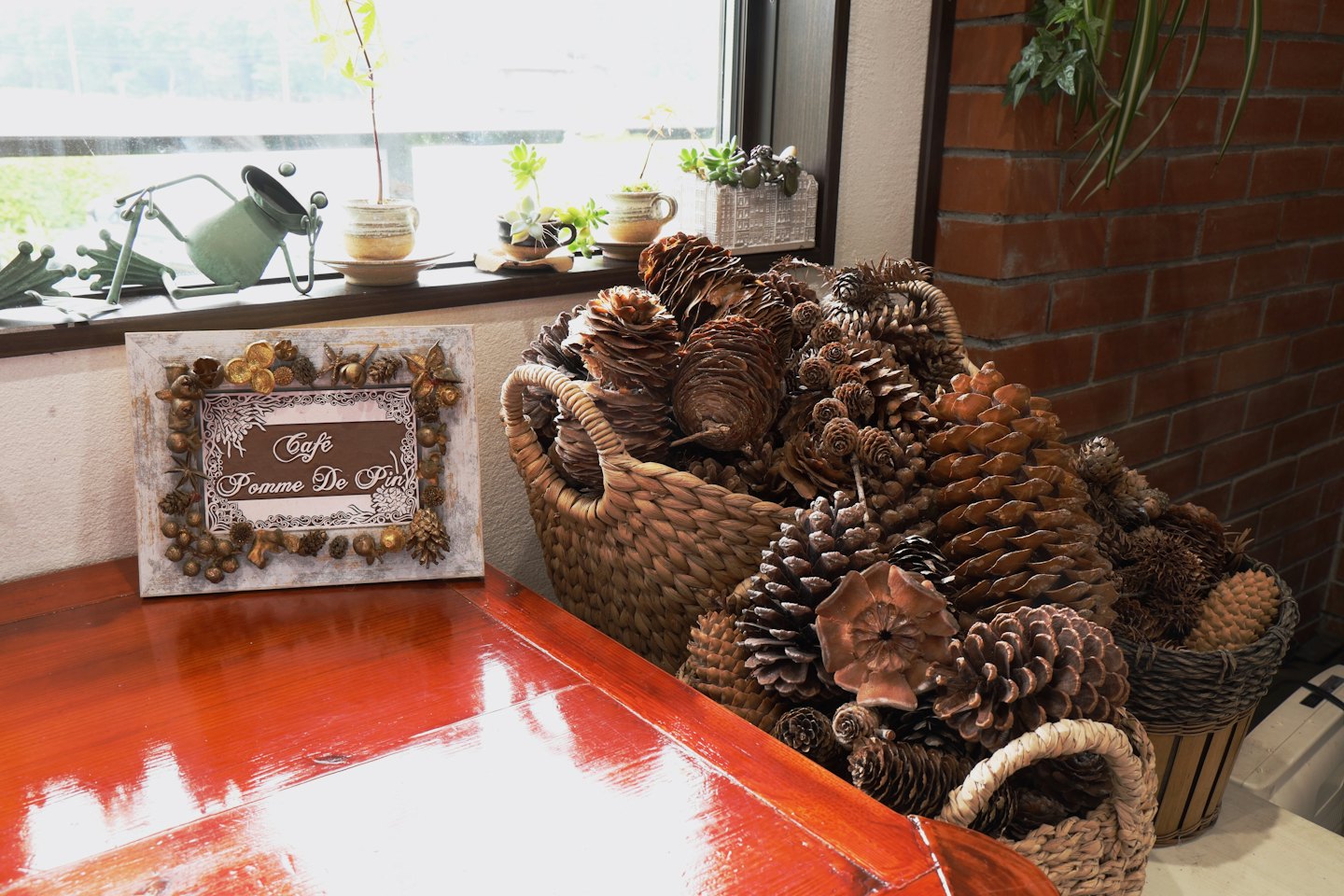 Decorated wooden sign sitting beside baskets filled with pinecones.