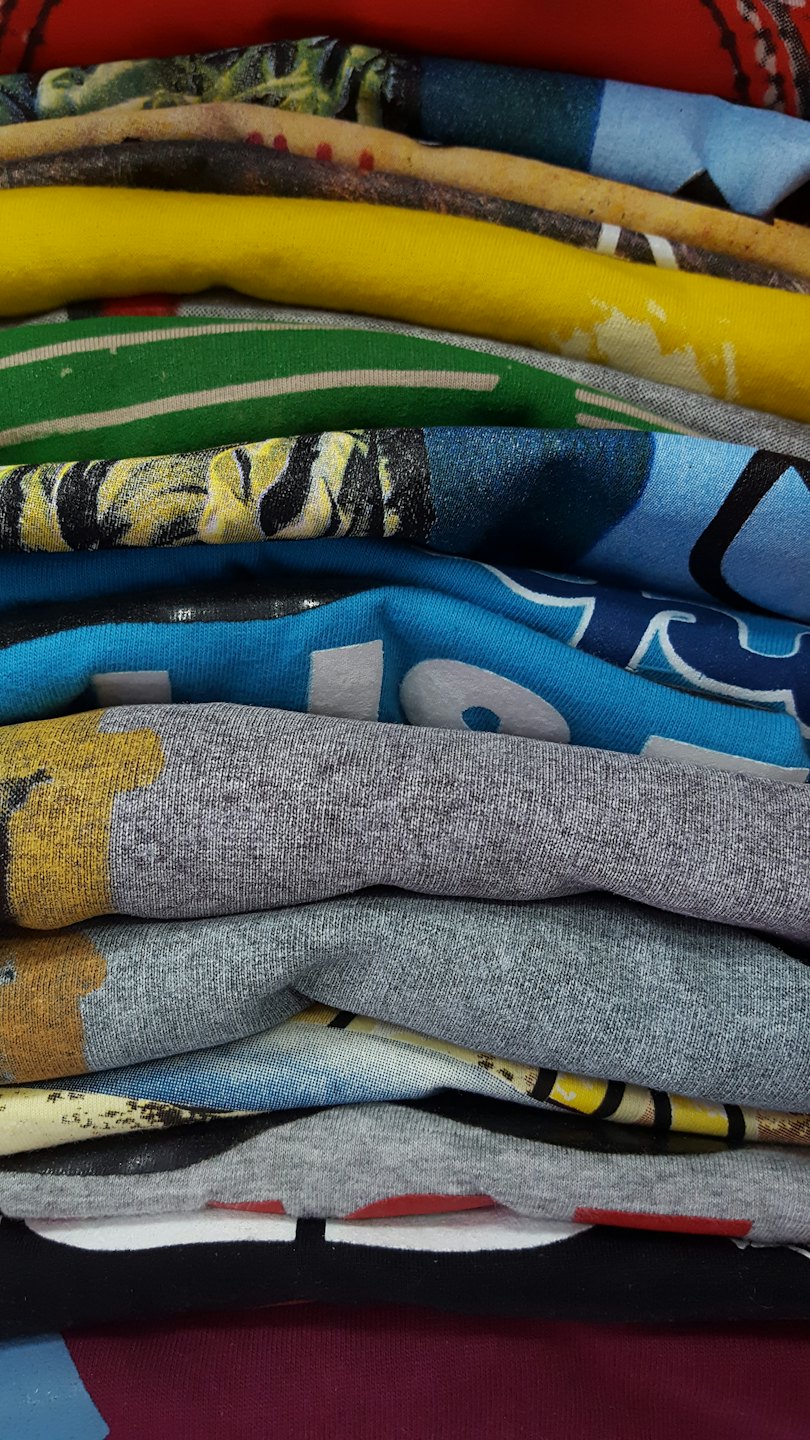 A stack of neatly folded multi-colored t-shirts.